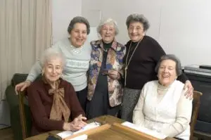 A joyful gathering of five senior ladies enjoying each other's company around a table, reminiscent of long-standing friendships and shared memories.